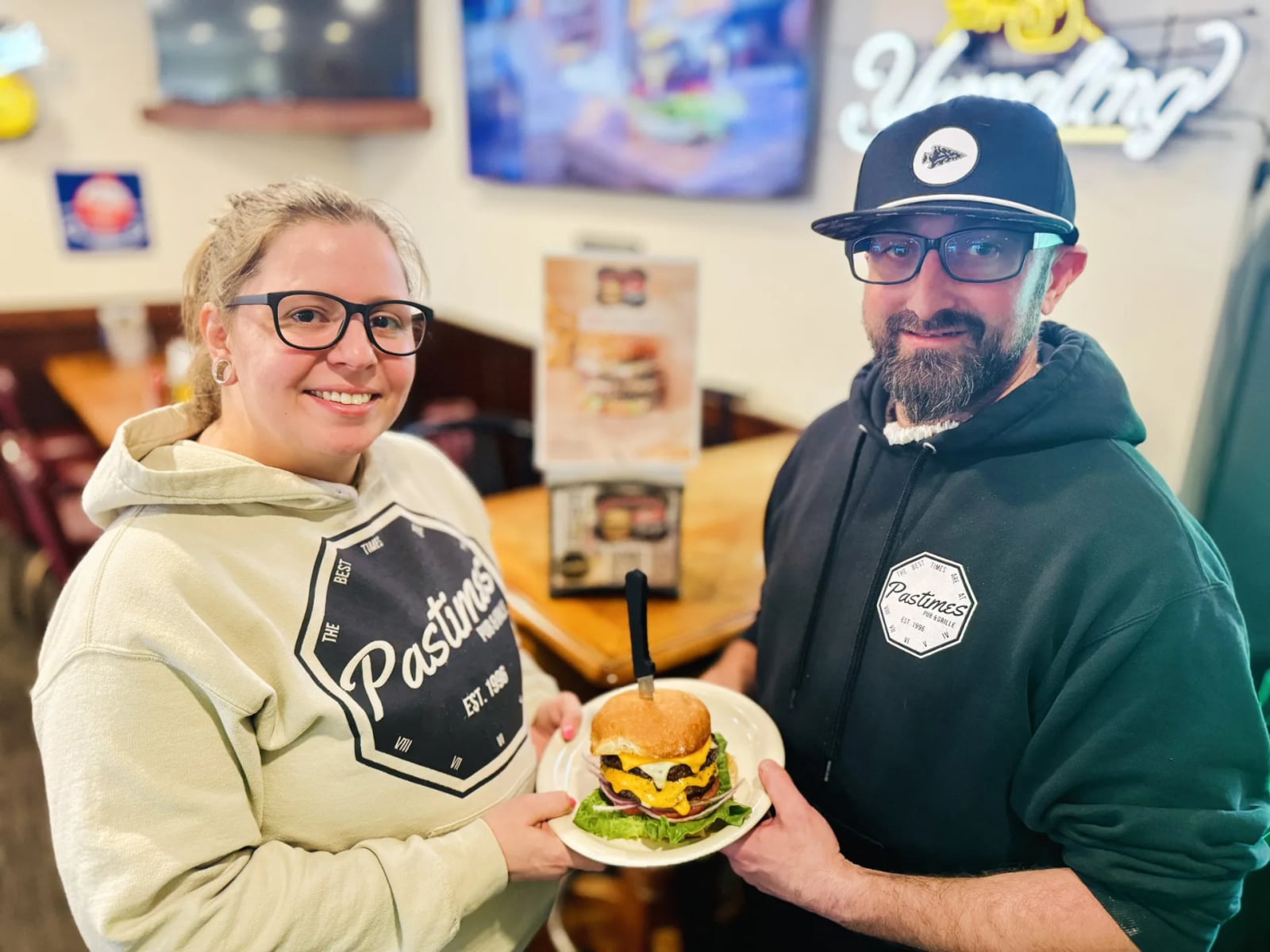 Adam and Kathe holding a burger at Pastimes Pub & Grille